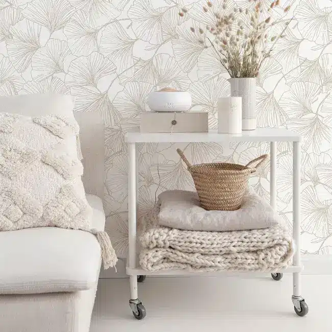 Papier peint adhésif dans une chambre blanche à la déco nature. Papier peint a feuilles dorées assorti à des coussins blanc