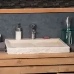 Vasque beige en pierre naturelle posee sur un meuble de salle de bain en bois