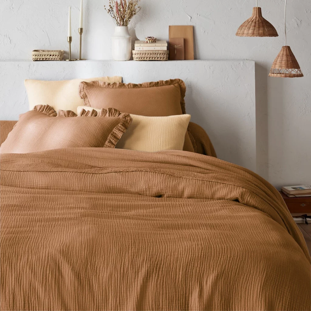 Chambre cosy et naturelle avec des murs en abricot clair, linge de lit blanc, mobilier en bois et éléments décoratifs en matières naturelles pour une ambiance douce et tendance.